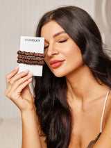 [Coffee] Brown mulberry silk scrunchies on SilkSilky card held beside model with dark hair 002
