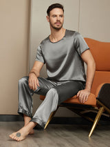 [Dark Gray] Seated front view of a men's mulberry silk pajama set with a short-sleeve crew-neck top and long pants in dark gray 004