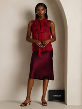 [Wine] A front studio view presents sheer burgundy bow-neck blouse and skirt, with the model placing one hand at the waist. 007