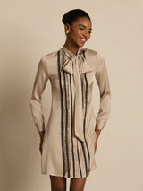 [Tan] Waist-up frontal view: beige long-sleeve tunic mini dress with vertical dark stripes, with both arms at the sides. 004