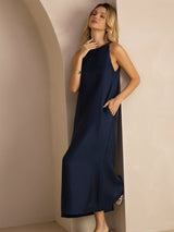 [Dark Blue] navy blue sleeveless scoop-neck midi dress, gathered waist and side pockets, full front view, hand lifted to the hair. 007