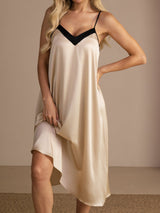 Close-up of ivory V-neck slip nightgown with black trim, showing dark V-neck trim and a flowing midi hem.