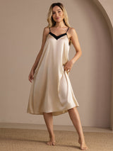 Ivory V-neck nightgown with black trim, full front view with one hand lifting the side hem.