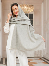[Light Gray] light gray rectangular shawl with fringed edges, styled front view, wrapped around the neck with one hand at the temple. 001