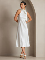 [White] The model faces forward in a white scarf-neck maxi dress, one hand at the waist. 006