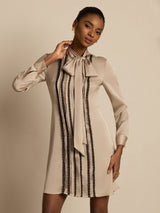 [Tan] Turned three-quarter view: beige long-sleeve tunic mini dress with vertical dark stripes, showing the side line. 003