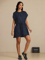 [Dark Blue] navy blue cap-sleeve short dress with drawstring waist and pockets, full front view, model standing with one knee bent. 007