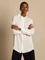 [White] Angled view: white long-sleeve collared blouse with black wide-leg trousers, with the model turned sideways. 003