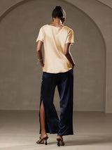 [Champagne] Back view of a woman wearing a champagne silk boat neck short sleeve top with navy satin pants 009