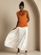 [Orange] Straight front crop of an orange cowl-neck top and white maxi skirt, with both arms lowered. 004