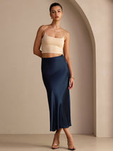 [Dark Blue] Navy blue glossy maxi skirt on a model in a full-body front view with one hand at her hip and weight shifted. 005