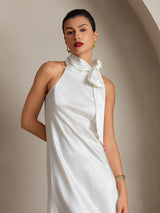 [White] White scarf-neck maxi dress in a front view cropped below the waist, hand behind back, the other down. 003