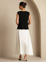 [Black] Rear studio view of a model wearing a black sleeveless cowl-neck top with a white maxi skirt. 002
