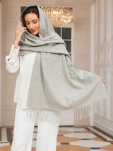 [Light Gray] light gray rectangular shawl with fringed edges, styled front view, one side extended outward to show the width. 003