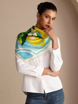 [Blue Lemon] Aqua-and-white square lemon scarf with green leaves and pale border, styled close-up, wrapped at neck, hand at temple. 004