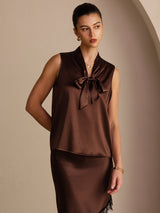 [Bitter Chocolate] Dark brown sleeveless tie-neck top on a model in a mid-length front view with both arms held behind her back. 003