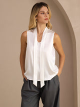 [White] White sleeveless tie-neck top on a model in a mid-length front view with one hand at her hip and torso angled. 003