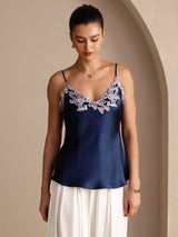 [Dark Blue] Navy blue camisole with slim straps and pale floral-lace V-neck, waist-up view, model looking down with arms relaxed. 001