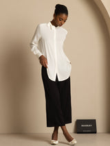 [White] Front full-length view: white long-sleeve collared blouse with black wide-leg trousers, with the lower hem in frame. 006