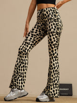 [Leopard] Front three-quarter crop: high-rise flared trousers with a black-and-cream leopard print, with one arm bent. 001