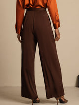 [Bitter Chocolate] Brown wide-leg trousers with a rust-orange blouse in a rear waist-to-shoes view, the wide legs and heels fully visible. 004