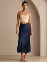 [Dark Blue] Navy blue glossy maxi skirt on a model in a full-body front view with arms relaxed and feet close together. 001