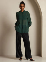 Dark green sheer silk long sleeve blouse with button cuffs and side slits, paired with black pants